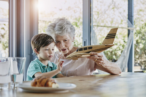 Enkel und Großmutter spielen mit einem Spielzeugflugzeug - RORF00474