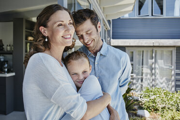 Glückliche Familie, die auf der Terrasse steht und ihre Tochter umarmt - RORF00494