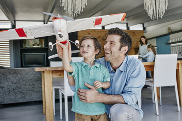 Vater und Sohn beim Spielen mit einem Spielzeugflugzeug - RORF00499