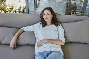 Frau sitzt entspannt auf einer Couch auf der Terrasse - RORF00503