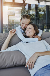 Daughter embracing mother sitting on terrace - RORF00505