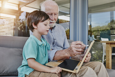Grandfather and grandson drawing on laptop-shaped blackboard - RORF00508