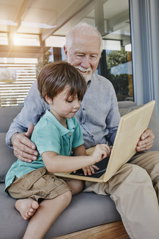 Grandfather and grandson drawing on laptop-shaped blackboard stock photo