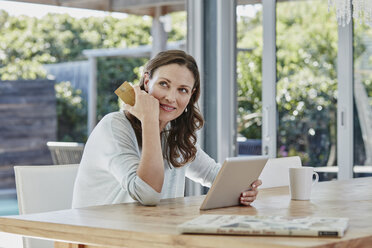 Woman sitting on terrace, doing online payment with credit card - RORF00518