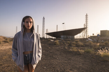 Spanien, Teneriffa, junge Frau in der Nähe eines verlassenen Flughafens mit Kopfhörern - SIPF01311