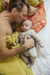 Father cuddling in bed with his newborn baby - MFF03452