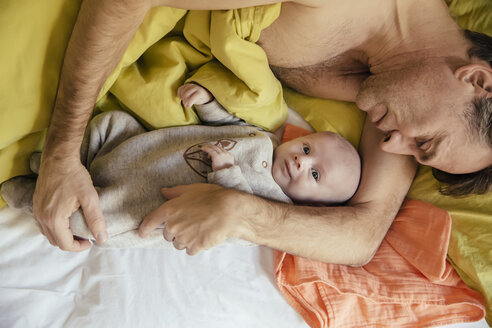 Vater kuschelt im Bett mit seinem neugeborenen Baby - MFF03455