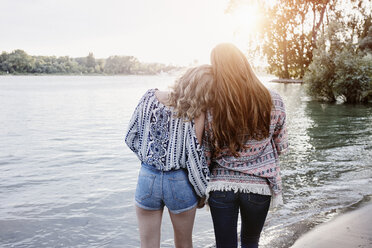 Back view of two teenage girls watching sunset at riverside - RORF00530