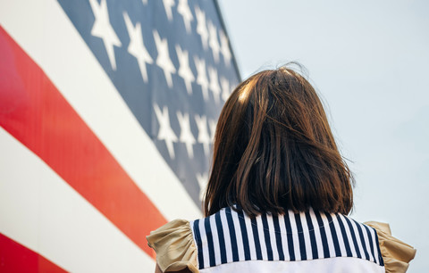 USA, Rückenansicht einer Frau vor Stars And Stripes, lizenzfreies Stockfoto