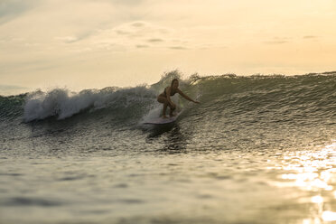 Indonesien, Bali, Frau beim Surfen im Sonnenuntergang - KNTF00608