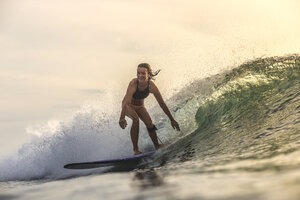 Indonesien, Bali, Frau beim Surfen im Sonnenuntergang - KNTF00609