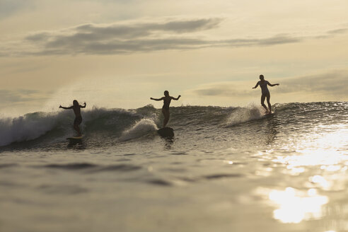 Indonesien, Bali, drei Surfer bei Sonnenuntergang - KNTF00610