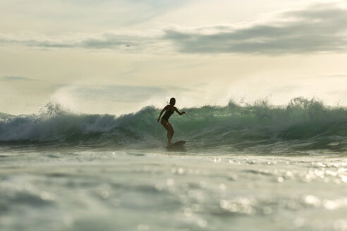 Indonesien, Bali, Frau beim Surfen im Sonnenuntergang - KNTF00612