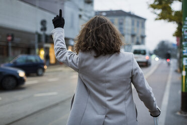 Rear view of man in the city hailing a taxi - MAUF00951