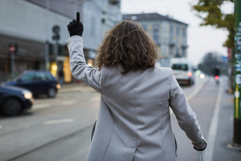 Rückansicht eines Mannes in der Stadt, der ein Taxi ruft - MAUF00951