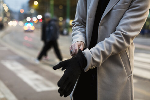 Nahaufnahme eines Mannes in der Stadt, der Handschuhe anzieht - MAUF00956