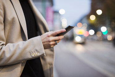 Nahaufnahme eines Mannes in der Stadt, der ein Mobiltelefon hält - MAUF00961