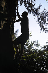 Silhouette of man climbing on rock - BTF00479