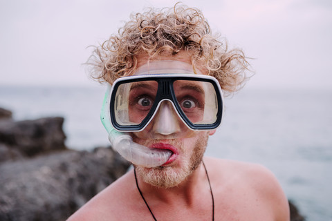 Porträt eines jungen Mannes mit Taucherbrille und Schnorchel, der lustige Gesichter zieht, lizenzfreies Stockfoto