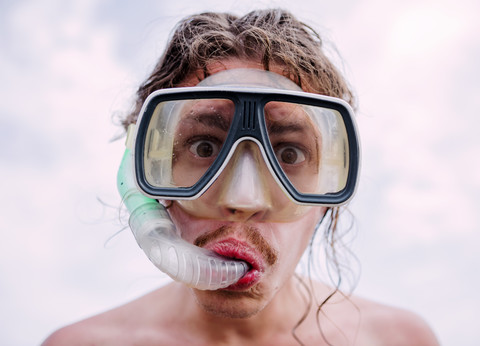 Porträt eines jungen Mannes mit Taucherbrille und Schnorchel, der lustige Gesichter zieht, lizenzfreies Stockfoto