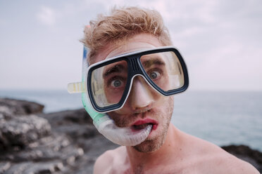 Portrait of young man with diving goggles and snorkel pulling funny faces - WVF00783