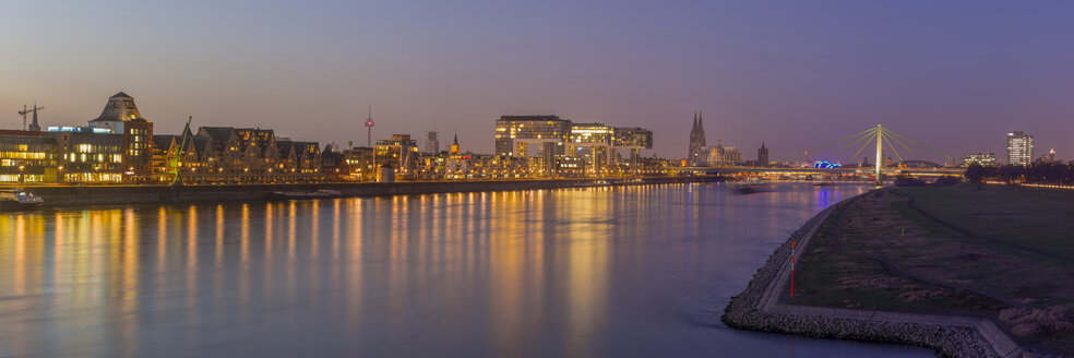 Deutschland, Köln, Panoramablick auf die beleuchtete Stadt mit dem Rhein im Vordergrund - WGF01040