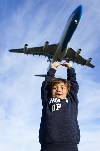 Junge greift nach landendem Flugzeug, lizenzfreies Stockfoto