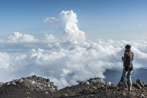 Italy, Sicily, hiker standing on Mount Etna looking at view stock photo
