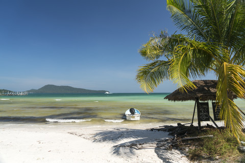 Kambodscha, Koh Rong Sanloem, Saracen Bay, Strand mit Palme und vertäutem Motorboot, lizenzfreies Stockfoto