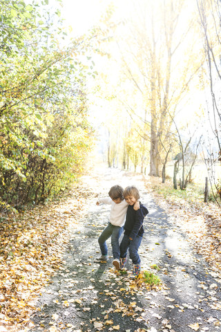 Zwei kleine Jungen spielen auf einer herbstlichen Landstraße, lizenzfreies Stockfoto