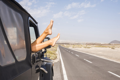 Spanien, Teneriffa, Beine einer Frau, die sich aus dem Autofenster lehnt, lizenzfreies Stockfoto