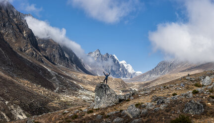 Nepal, Himalaya, Khumbu, Everest region, Khunde, woman cheering on rock - ALRF00839