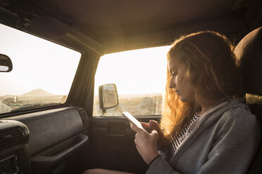 Frau im Auto schaut auf ihr Handy - SIPF01329