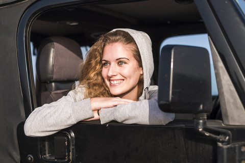 Portrait of happy young woman leaning out of car window stock photo