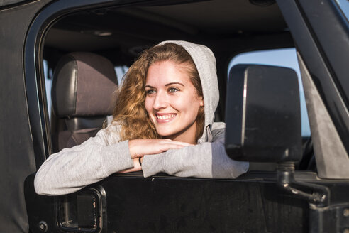 Porträt einer glücklichen jungen Frau, die sich aus dem Autofenster lehnt - SIPF01331