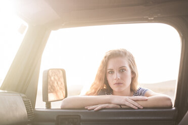 Porträt einer jungen Frau, die sich an ein Autofenster lehnt und hineinschaut - SIPF01333