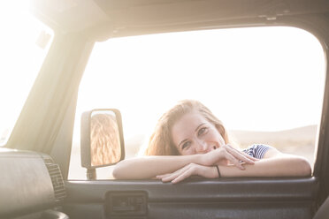 Porträt einer jungen Frau, die sich an ein Autofenster lehnt und hineinschaut - SIPF01334