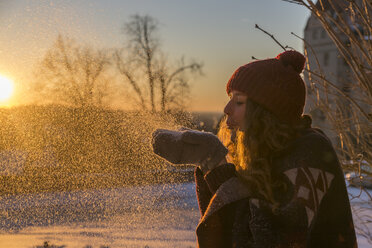 Young woman blowing snow at sunset - SARF03119