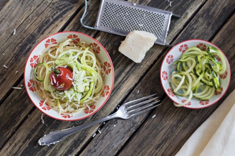 Schüssel mit Spaghetti, Zucchini-Spaghetti, Guacamole, Kirschtomaten und geriebenem Parmesan, lizenzfreies Stockfoto