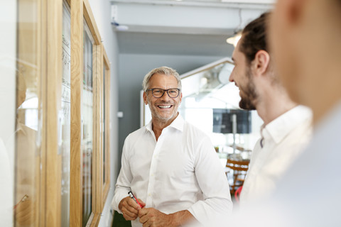 Smiling businessman looking at colleagues in office stock photo