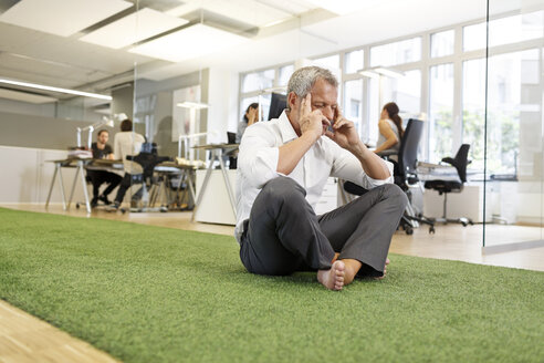 Businessman meditating in office - PESF00411