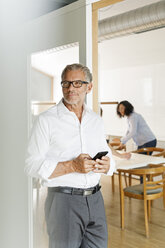 Geschäftsmann mit Mobiltelefon im Büro - PESF00415