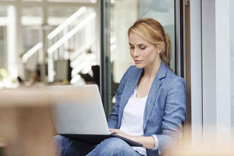 Frau benutzt Laptop im Büro, lizenzfreies Stockfoto