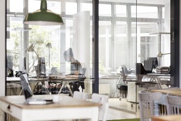 Mann arbeitet in einem modernen Büro hinter einer Glaswand - PESF00501