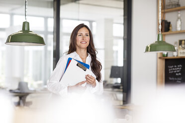 Smiling businesswoman in office holding clipboard - PESF00504