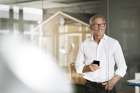 Geschäftsmann mit Mobiltelefon im Büro - PESF00511