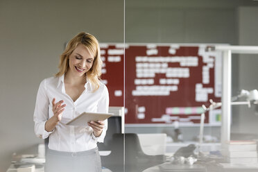 Smiling businesswoman using tablet in office - PESF00514