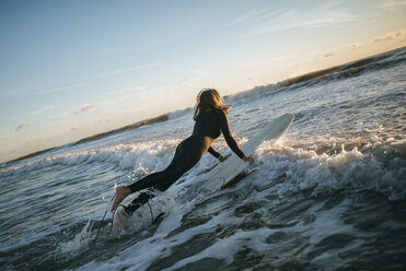 Surferin im Neoprenanzug mit Surfbrett im Meer - KIJF01100