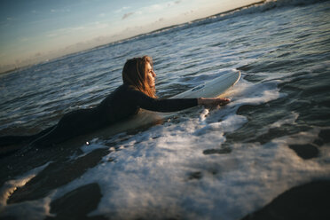 Woman lying on surfboard in the sea - KIJF01101