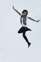 Frau springt in die Luft vor grauem Hintergrund - UUF09768